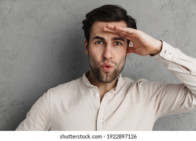 Surprised handsome unshaven guy posing and looking ar camera isolated over grey wall - Shutterstock ID 1922897126