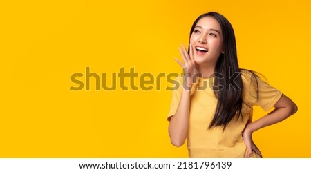 Surprised happy Asian woman looking copy space in excitement Expressive facial expressions Presenting product Beautiful girl act like a telling to customer Isolated on yellow background copy space