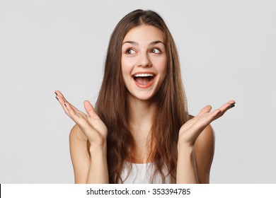 Surprised happy beautiful woman looking sideways in excitement. Isolated on gray background