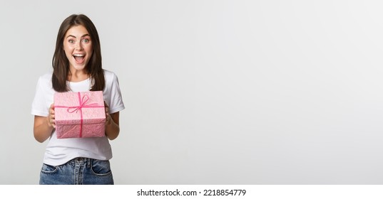 Surprised Happy Birthday Girl Receiving Wrapped Gift, White Background.