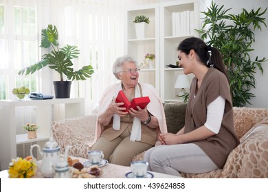 Surprised And Happy Grandma Opening A Gift From Her Granddaughter