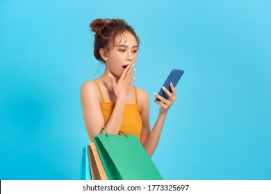 Surprised Happy Woman Holds Cheap Paper Shopping Bags Looks At Phone