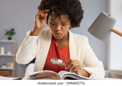Surprised inquisitive black woman with magnifying glass takes off glasses as she sees an amazing curious fact in the book she's reading. Shocked financial advisor studying business documents in office