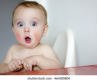 surprised kid sitting at table. child's eyes widened and mouth opened in amazement. copy space for your text