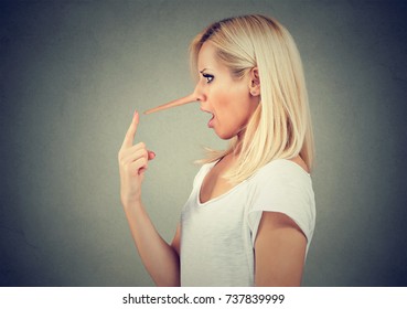 Surprised liar woman with long nose isolated on gray wall background. Lies concept. Human emotions, feelings.