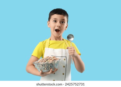 Surprised little chef with spoon and bowl of cereal rings on blue background - Powered by Shutterstock