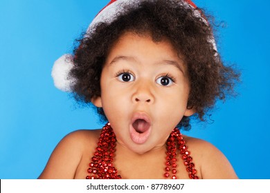 Surprised Little Child In Christmas Hat Against Blue Background