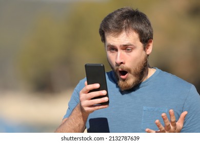 Surprised Man Checking Smart Phone Content Standing Outside In A Lake