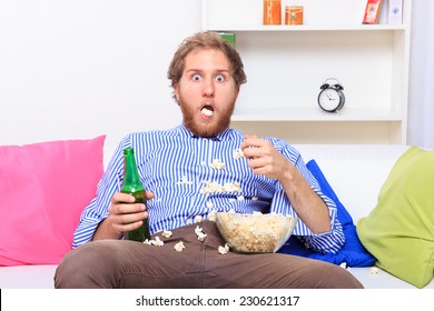 Surprised Man Eating Popcorn On The Sofa At Home 