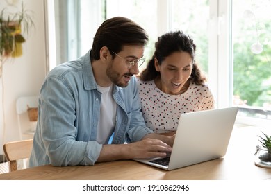 Surprised married couple sit by desk look at laptop screen read email with profitable proposal. Amazed millennial husband wife receive unexpected money income get present discount offer from web store
