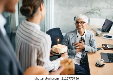 Surprised mature businesswoman receiving Birthday cake from her coworkers in the office. - Powered by Shutterstock