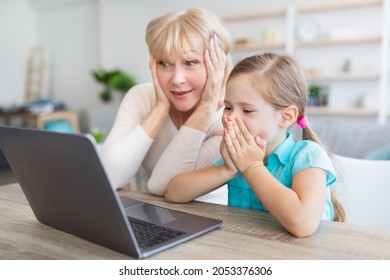 Surprised Mature Woman And Kid Girl Looking At Computer Screen Using Laptop, Amazed Granny And Granddaughter Excited With Unbelievable Internet News, Shocked By Sale Offers Covering Mouth And Ears