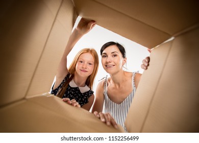 The Surprised Mom And Daughter Unpacking, Opening Carton Box And Looking Inside. The Package, Delivery, Surprise, Gift Lifestyle Concept. Human Emotions And Facial Expressions Concepts