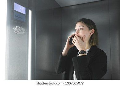 Surprised office worker is talking on her phone looking at the number in the elevator. Young businesswoman is in hurry, over the phone, looking at the floor number in the lift. - Powered by Shutterstock