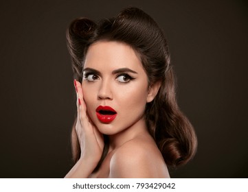 Surprised Pin Up Girl Holds Cheek By Hand. Comic Woman With Curls Retro Hair Style. Wow. Presenting Your Product. Shocked Lady Isolated On Black Dark Studio Background.