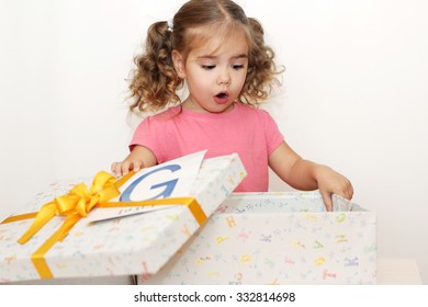 Surprised Pretty Girl Opening The Gift Box With G Letter On It, Indoor Portrait