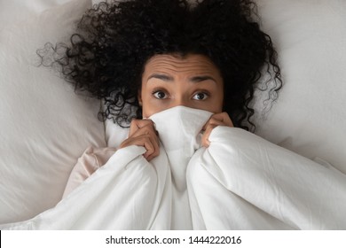 Surprised Scared Funny African Girl Lying In Bed Covering Face With Blanket, Young Black Woman Awake From Sleep Hiding Peeking From Duvet Feel Shy Afraid Or Bad Dream Nightmare Embarrassed, Top View