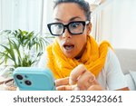 Surprised and scared woman reacting to a phishing attempt on her smartphone at home, worried about fraud and virus threats, concept of online scams and personal data protection