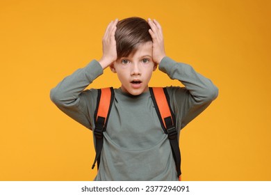 Surprised schoolboy covering head with hands on orange background - Powered by Shutterstock