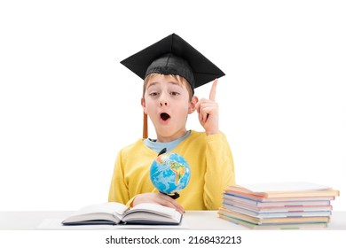 Surprised Schoolboy In Student Hat Raised Index Finger Up. Concept Idea Or Insight In Child. Excellent Student. White Background.