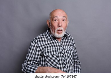 Surprised senior man in casual checkered shirt grimacing at gray studio background with copy space. Shok and excitement concept - Powered by Shutterstock