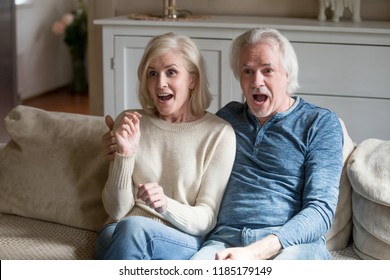 Surprised Senior Middle Aged Couple Viewers Feeling Amazed Watching New Reality Show On Television Channel, Astonished Shocked Old Mature Family Looking Excited By Unbelievable Breaking News On Tv