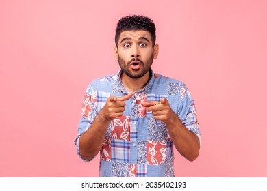 Surprised Shocked Bearded Man Wearing Blue Casual Style Shirt Looking With Big Eyes And Open Mouth, Pointing Finger At Camera, Suspecting You. Indoor Studio Shot Isolated On Pink Background.