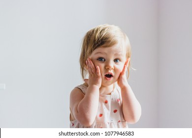 Surprised shocked child toddler girl with hands on her cheeks isolated on light background - Shutterstock ID 1077946583