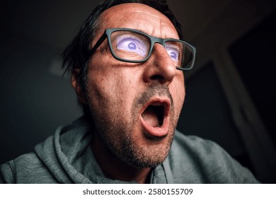 Surprised and shocked man looking at computer screen while browsing internet or social media, selective focus