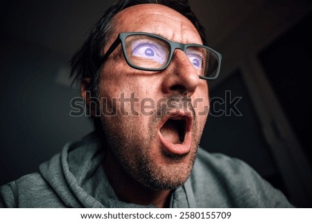 Surprised and shocked man looking at computer screen while browsing internet or social media, selective focus
