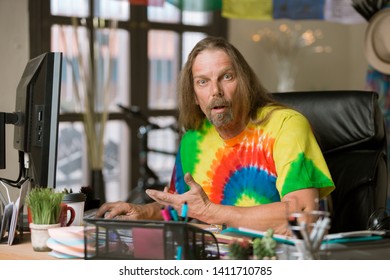 Surprised Or Shocked Man In Tie Dye Shirt At His Desk