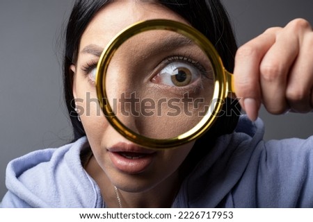 Surprised, shocked Woman looking through a magnifying glass, searching for a Find concept . Funny humor image