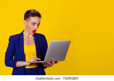 Surprised Shocked Young Business Woman Short Hair Using Laptop Looking At Computer Screen Blown Away In Stupor On Yellow Background. Human Face Expression, Emotion, Feeling, Body Language, Reaction