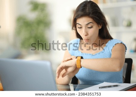 Surprised student checking smartwatch at home