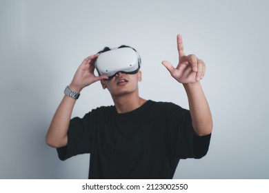 Surprised Teen Male Student Use Vr Glasses And Looks At Empty Space With Gray Background, Studio Shot.Virtual Gadgets For Entertainment, Work, Free Time And Study. Virtual Reality Technology Concept.