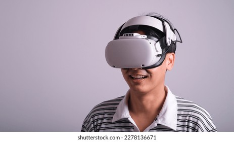 Surprised teen male student use vr glasses and looks at empty space with gray background. Virtual gadgets for entertainment, work, free time and study. Virtual reality metaverse technology concept. - Shutterstock ID 2278136671