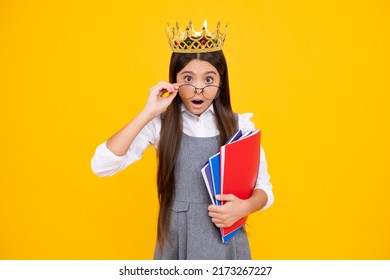 Surprised teenager girl. Schoolgirl in school uniform and crown celebrating victory on yellow background. School child hold books. Education graduation, victory and success.
