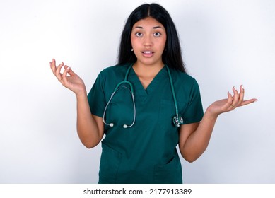 Surprised Terrified Doctor Hispanic Woman Wearing Surgeon Uniform Over White Background Gestures With Uncertainty, Stares At Camera, Puzzled As Doesn't Know Answer On Tricky Question, People, Body Lan