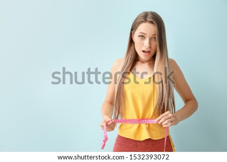 Surprised woman with measuring tape on light background. Diet concept