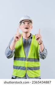 Surprised young architect pointing up. Amazed engineer pointing at an advertisement. Engineer with astonished face pointing at blank space - Shutterstock ID 2365434887