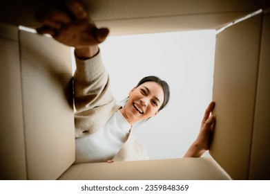 Surprised young asian woman unpacking. Opening carton box and looking inside. Packaging box, delivery service. Human emotions and facial expression - Powered by Shutterstock