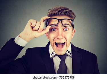 Surprised young business man taking of glasses