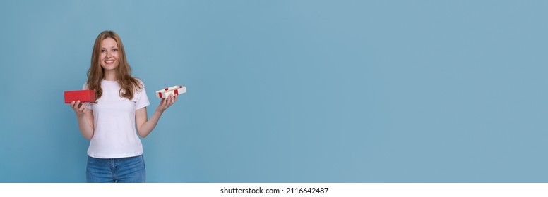 Surprised Young Caucasian Woman Holding Red Gift Box And Shocked With Open Mouth Standing On Blue Background Beautiful Girl Happy Smile Holding Generic Box Suitable For Any Holiday Use For Advertising