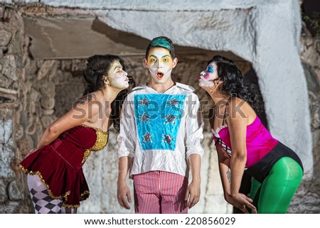 Surprised young cirque clown with females blowing kisses