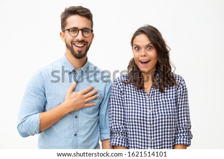 Surprised young couple looking at camera. Front view of excited young man and woman standing together and looking at camera on white background. Emotion concept