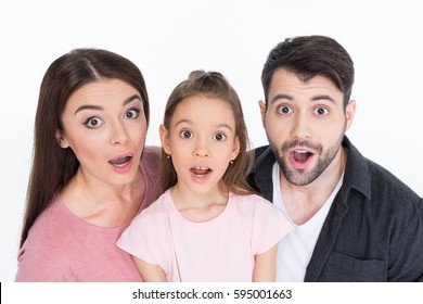 Surprised Young Family Looking At Camera Isolated On White