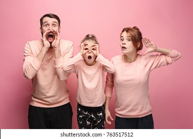 Surprised Young Family Looking At Camera On Pink