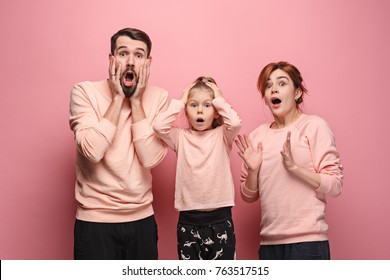 Surprised Young Family Looking At Camera On Pink