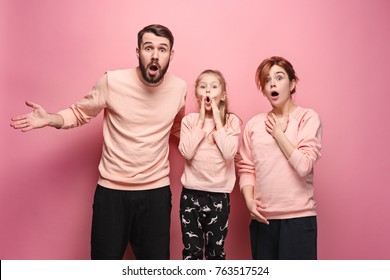 Surprised Young Family Looking At Camera On Pink