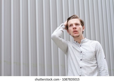 Surprised Young Man With An Arm In His Hair. Seeing Something Strange. Activity. Emotions. Shocked Man. Urban Street Style. Copy Space. Gray Background.